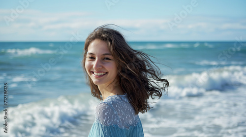 Lida mulher com cabelo marrom sorrindo na praia com o mar no fundo em um dia ensolarado photo