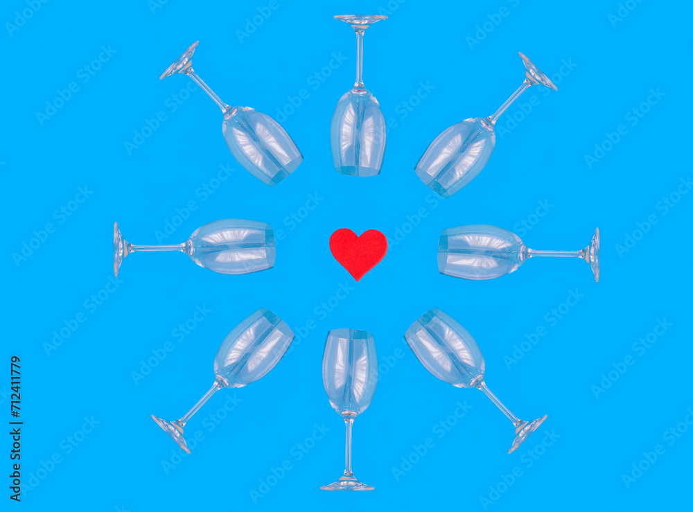 Red heart and empty wineglasses on the blue background. Top view. Close-up. Red heart and empty wineglasses on the blue background. Top view. Close-up.