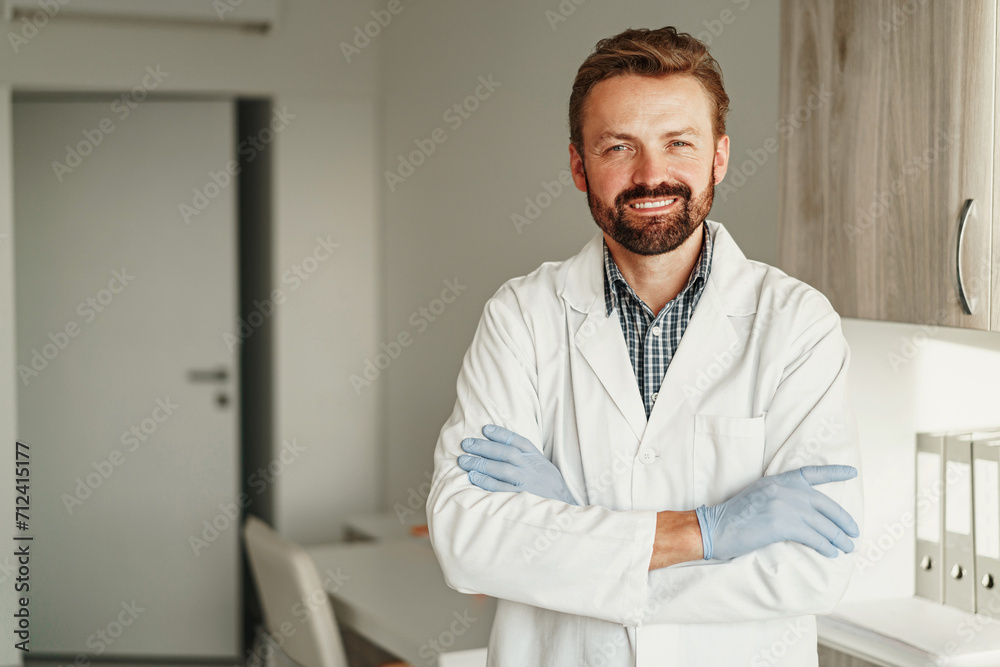 Smiling doctor in uniform standing at hospital and looking camera with smile