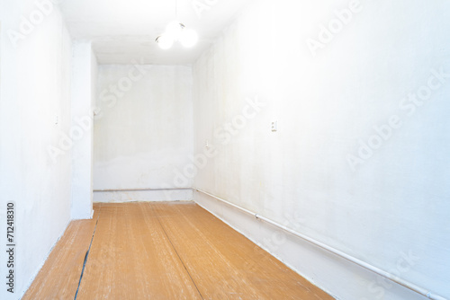 Wallpaper Mural empty room with signs of wear, white walls that need repainting, an old wooden floor with visible damage, and a simple ceiling light fixture, suggesting a space ready for renovation or restoration Torontodigital.ca