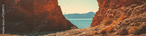 Rocky seascape on a sunny day. Seascape in daylight. View of the sea between two rocks. Horizontal banner