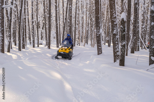 Woman on a snowmobile moving in the winter forest in the mountains of the Southern Urals © 02irina