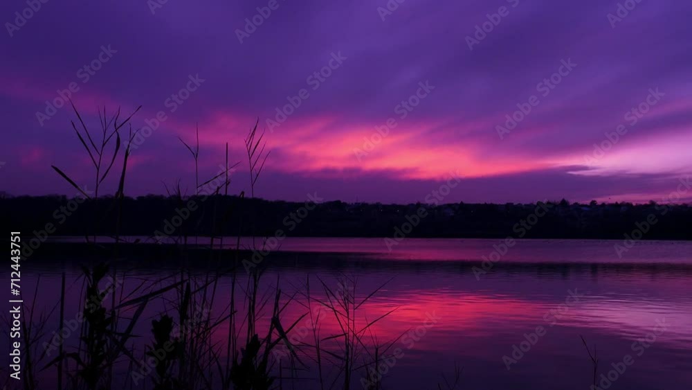 Colorful clouds at sunset or sunrise. Landscape with a pink and purple sky above a lake.