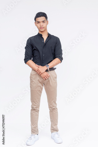 A portrait of a young Filipino man standing confidently in smart casual wear against a white background. photo