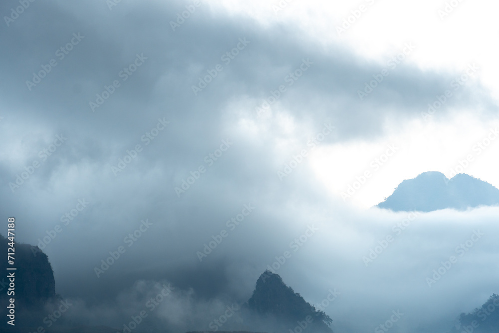 Obraz premium Landscape morning fog in mountain viewpoint of Khao Chang Noi Phu Langka Phayao Province of Thailand. Hills are lined with beautiful green fields and forests. Under sky is gloomy in the morning.