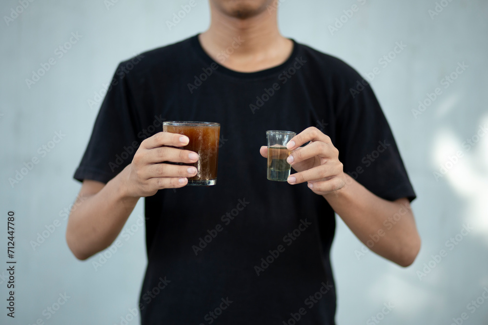 Front view close up of a man hands holding a coffee cup and liquid sugar at home Front view close up of a man hands holding a coffee cup and liquid sugar at home