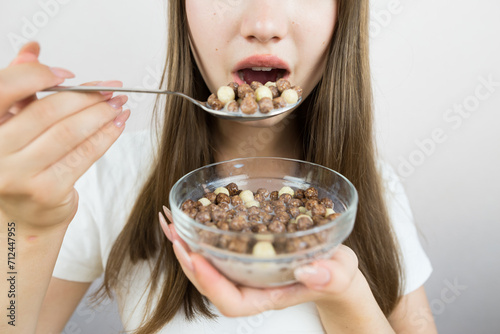 young beautiful woman eating dry breakfast balls with milk