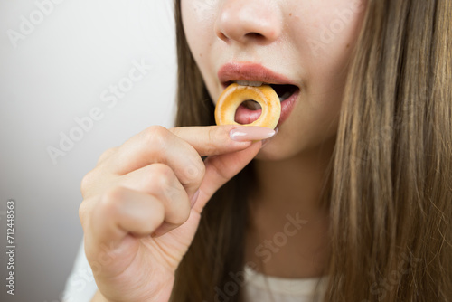 young beautiful girl eating bagels  close-up  crop photo.Attractive brunette sexy woman eating a delicious donut.