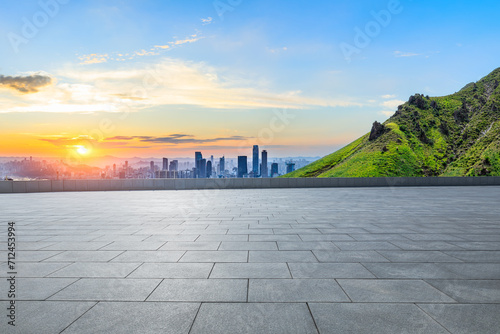 Empty square floor and green mountain with city skyline scenery at sunset