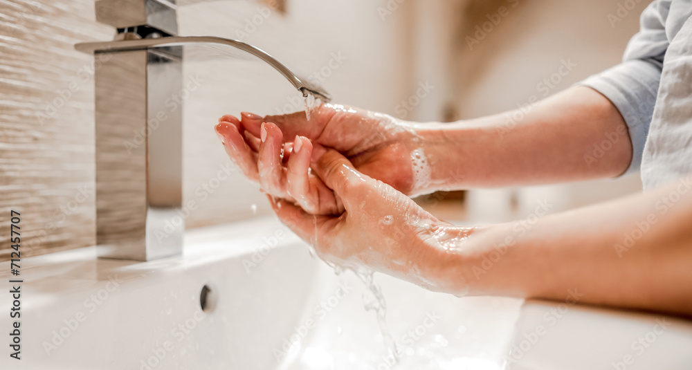 Fototapeta premium Girl washing hands with soap foam in bathroom with steel faucet. Hygiene and cleaning procedure to prevent virus and desease