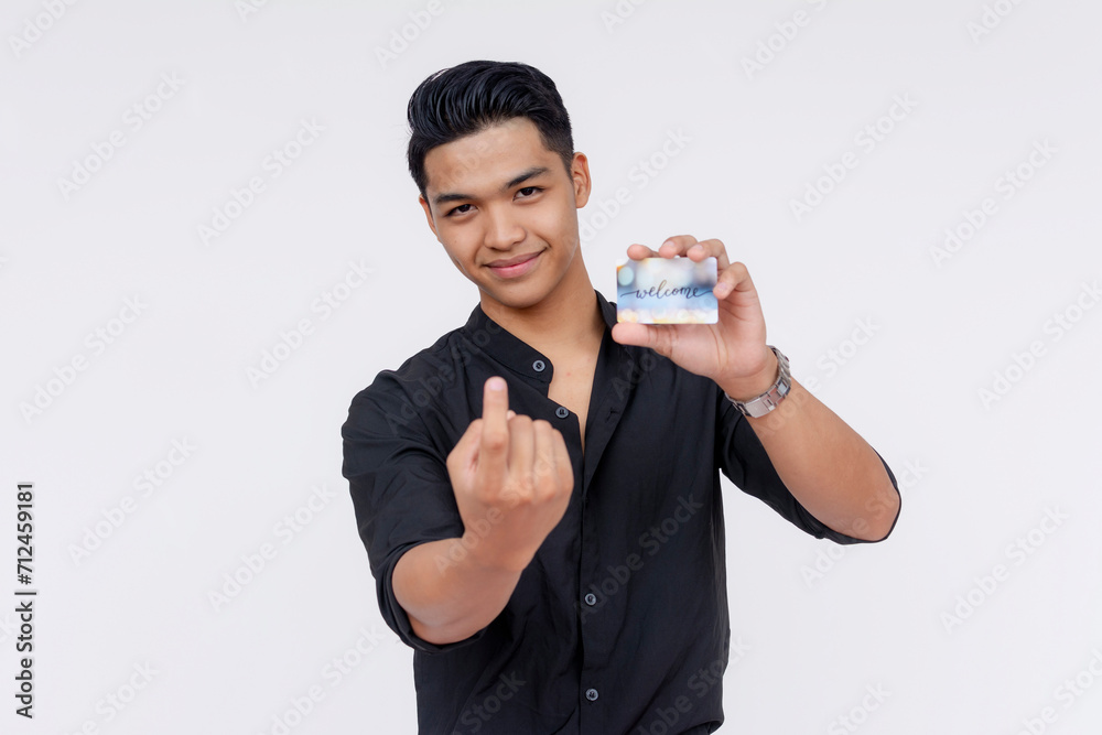 A handsome young asian guy showing his hotel key card with the word welcome on it. Inviting someone to come to his room. Studio shot, with white background. A handsome young asian guy showing his hotel key card with the word welcome on it. Inviting someone to come to his room. Studio shot, with white background.
