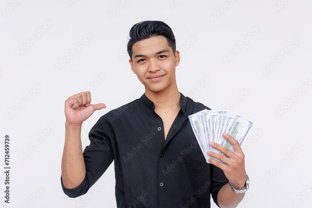 Smiling young Filipino male showing off cash in one hand and promoting himself with confidence on a white background. Smiling young Filipino male showing off cash in one hand and promoting himself with confidence on a white background.