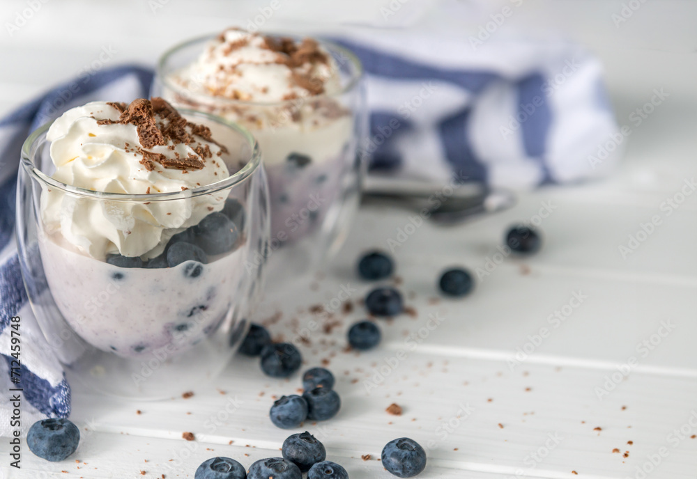 Dessert from yogurt with blueberries and chocolate on a white wooden background Dessert from yogurt with blueberries and chocolate on a white wooden background
