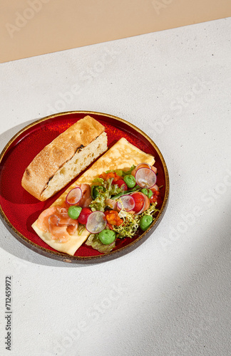 A bird's eye view of an omelette with salmon and avocado mousse, accompanied by ciabatta bread