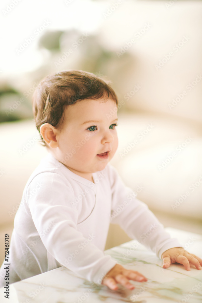 Portrait of adorable baby at home, wearing white onesie