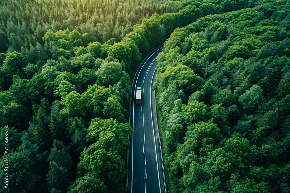 Drone's eye view: Car and hydrogen energy truck drive on highway through lush forest. Aerial scene promoting sustainable transport and eco-friendly electric vehicles.