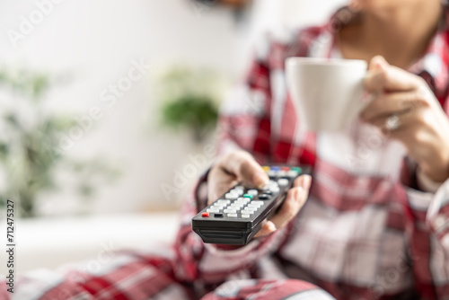 Young brunette woman relaxing on sofa at home watching tv and drinking coffee - Close up