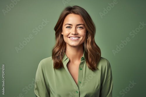 Portrait of smiling businesswoman in green shirt on green background.