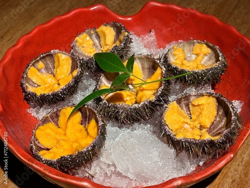 Beautiful sea urchin on a plate. Close up and top view. Wooden table, ice and leaf. photo