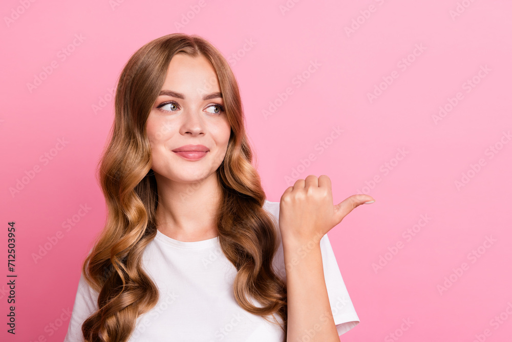 Portrait of young beautiful woman with brown curls hair pointing finger empty space cream lotion brand isolated on pink color background Portrait of young beautiful woman with brown curls hair pointing finger empty space cream lotion brand isolated on pink color background