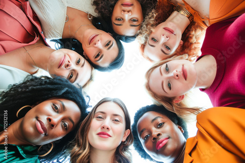 A diverse group of young women forming a circle and looking down into the camera. © joris