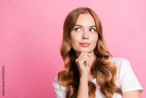 Portrait of dreamy nice girl curly hairdo dressed stylish t-shirt hand on chin look at offer empty space isolated on pink color background