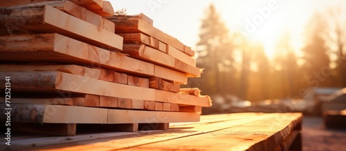 Close-up view of stacked pine tree planks with bark in a sunny outdoor setting. Warehouse with wood waste from sawmill production. Soft focus. Copy space. Focus on lumber industry. photo