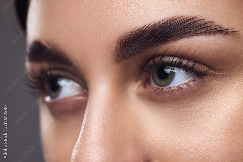 Close-up of a woman's eyes with well-defined eyebrows, full lashes, and smooth skin, highlighting meticulous grooming. Concept of beauty, eyebrow shaping kit, grooming and natural brow look. Close-up of a woman's eyes with well-defined eyebrows, full lashes, and smooth skin, highlighting meticulous grooming. Concept of beauty, eyebrow shaping kit, grooming and natural brow look.