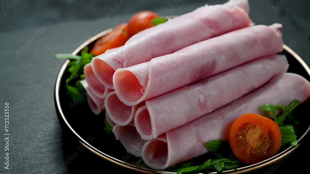 Delicious turkey ham slices in a black plate, over dark background