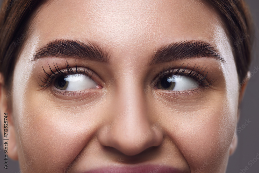 Fototapeta premium Close-up of female face, eyes with well-groomed eyebrows, clear eyes, and smooth skin against neutral grey background. Concept of medical, techniques for vision, and focusing for eyes. Ad
