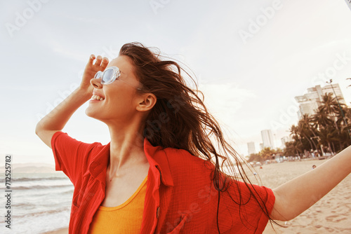 Serene Portrait: A Smiling Woman With Sunglasses Enjoying Freedom and Vibrant Colors at the Beach