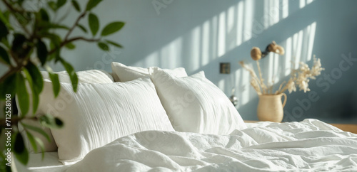  A nicely made white bed with pillows and linen, with a large window letting in sunlight. photo
