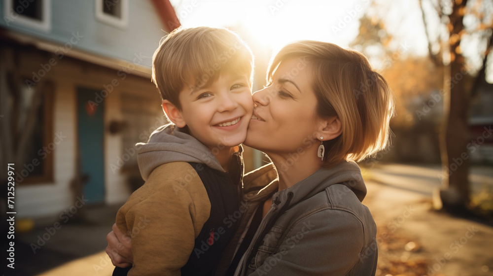 Caucasian boy kisses his mother outside the house. Caucasian boy kisses his mother outside the house.