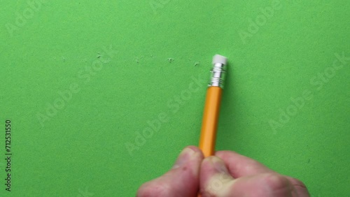 erasing with a yellow pencil with an eraser on a green background