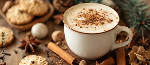 Spiced latte served in a mug with cinnamon, nutmeg, and cookies.