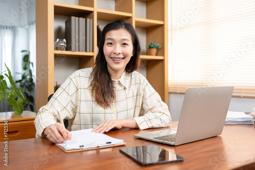 Successful Asian woman working in the office Happy businesswoman analyzes weekly schedule in her notebook. Smiling and looking at the camera
