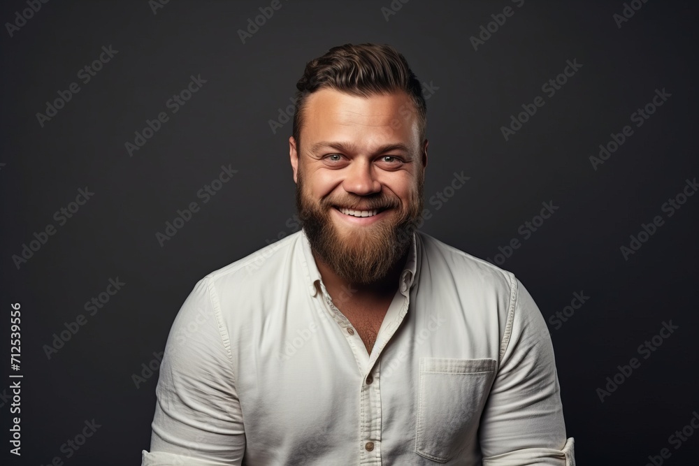 Portrait of a smiling bearded man in a white shirt over dark background.