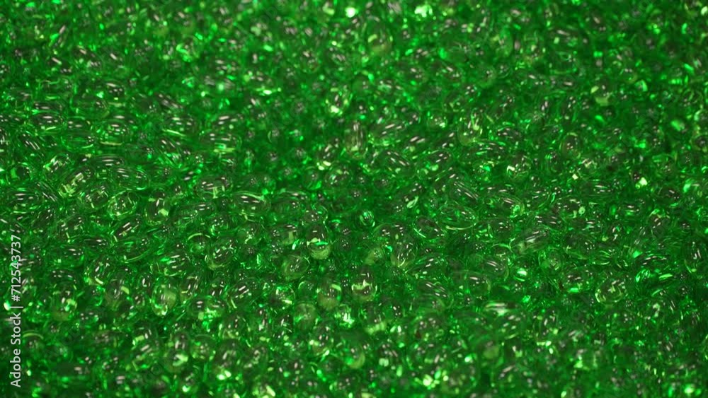 Multitud de píldoras verdes sobre una cubeta.