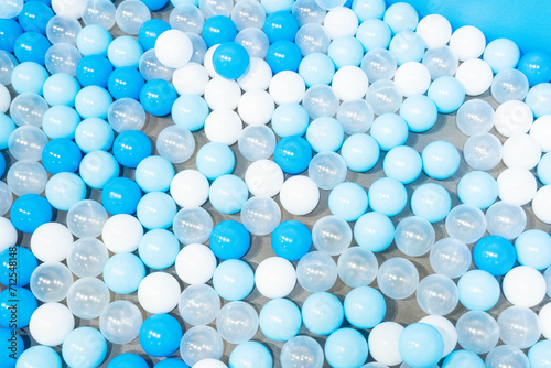 Colored plastic balls in pool of kindergarten school White and blue plastic balls pit in game room Many white balls background.