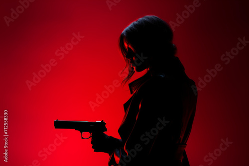Young woman with gun in dark with back red light. Profile silhouette view 