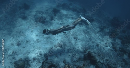 Woman freediver glides on deep in tropical blue sea. Freediver girl swims underwater photo