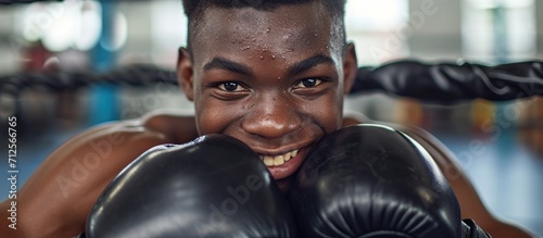 Smiling young boxer at the gym wearing gloves.