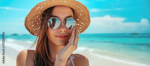 Young woman applying sunscreen at beach.