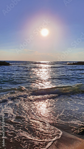 Colorful sunset with large sun under the sea waves.