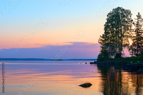 Summer evening landscape of a calm lake with reflected sunlight. © Ludmila