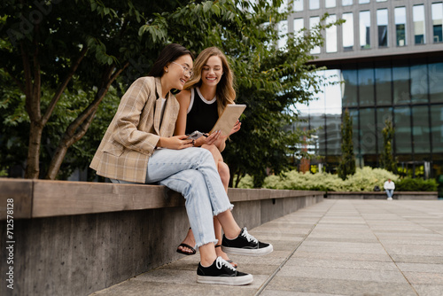young pretty women sitting outside in street doing business