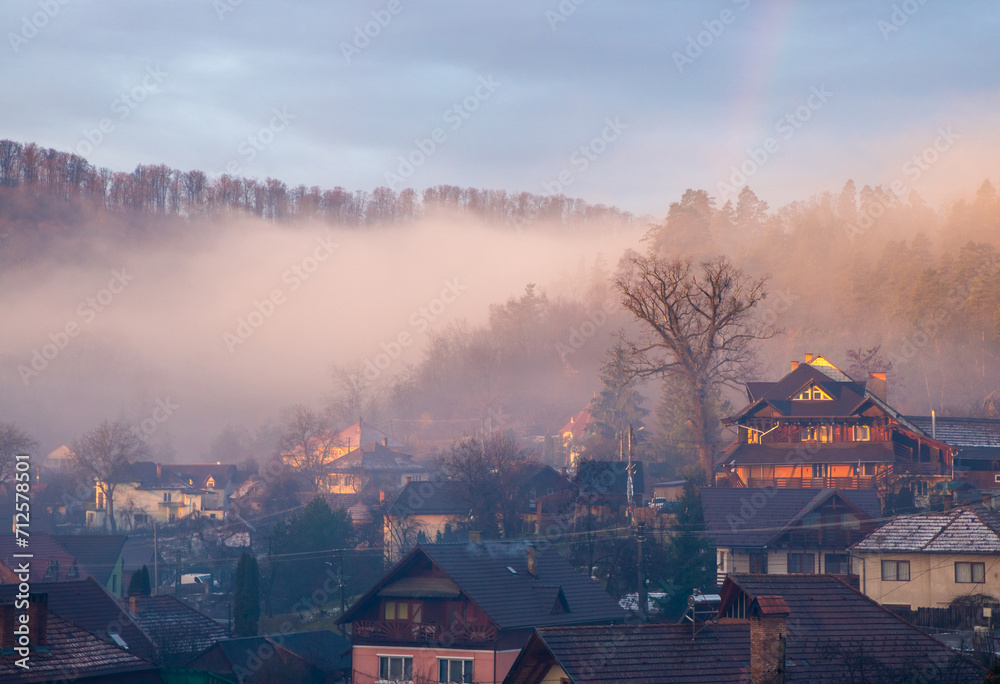 Evening landscape over the houses in the village. Golden hour with fog over the countryside