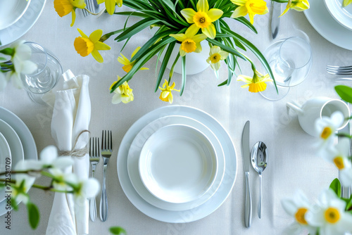 table setting. Plates and cutlery with spring flowers daffodils on a light table photo