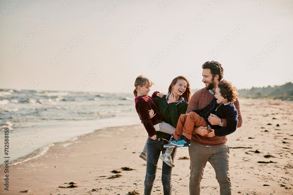 Joyful family playing and laughing together on the beach at sunset Joyful family playing and laughing together on the beach at sunset