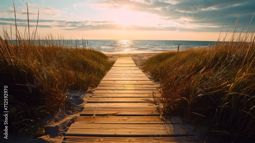  a wooden walkway leading to the beach with the sun setting in the distance behind the grass and the ocean in the distance. photo